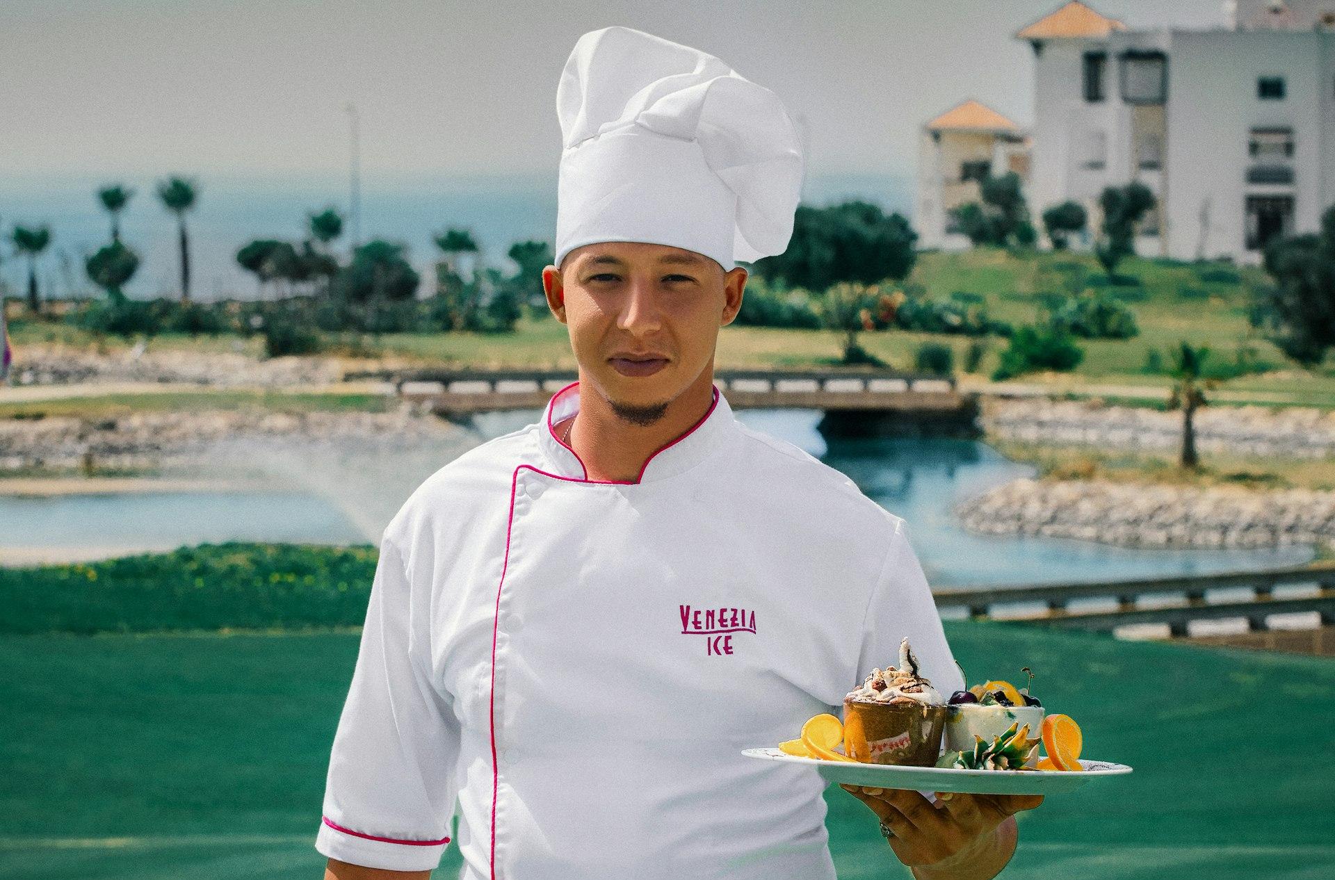 woman in white chef uniform holding green plate with food